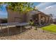 Backyard view featuring a trampoline, gravel landscaping, manicured lawn and a covered patio at 12238 W Patrick Ct, Sun City, AZ 85373