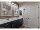 Bathroom with dual vanities, wood accent wall, and decorative mirrors at 12238 W Patrick Ct, Sun City, AZ 85373
