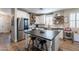 Open-concept kitchen with island, stainless steel refrigerator, white cabinets, and wood floors at 12238 W Patrick Ct, Sun City, AZ 85373