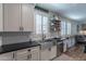 Bright kitchen with white cabinets, dark countertops, stainless steel sink, and open shelving at 12238 W Patrick Ct, Sun City, AZ 85373