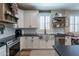 Well-lit kitchen with white cabinets, black countertops, stainless steel appliances, and decorative shelves at 12238 W Patrick Ct, Sun City, AZ 85373
