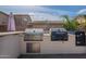 A built-in stainless steel grill, oven and warming drawer featured in this outdoor kitchen at 12238 W Patrick Ct, Sun City, AZ 85373