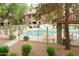 Community pool area with lounge chairs and tables, surrounded by mature landscaping and a wrought iron fence at 15252 N 100Th St # 1172, Scottsdale, AZ 85260