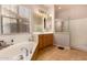 Bright bathroom with a corner tub under a large window, walk-in shower with glass door, and single-sink vanity at 15416 W Valentine St, Surprise, AZ 85379