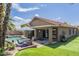 Charming backyard with green lawn, pool, outdoor dining, and patio ideal for relaxing and entertaining at 15848 W Calavar Rd, Surprise, AZ 85379
