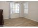 Bright bedroom with two windows, neutral paint, and wood-look tile flooring at 17128 N Princess Pl, Surprise, AZ 85374