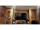 A living room featuring wood-paneled walls, a large-screen TV, and decorative items at 18177 W Tasha Dr, Surprise, AZ 85388