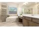Bright bathroom featuring a shower, tub, and vanity with double sinks and wood-look tile floors at 20256 E Canary Ct, Queen Creek, AZ 85142