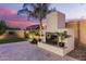Outdoor fireplace with travertine tile, palm tree, and beautiful pavers at dusk at 20256 E Canary Ct, Queen Creek, AZ 85142