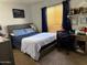 Cozy bedroom featuring a bed, a desk with a rolling chair, and a window with blue curtains at 22966 W Hopi St, Buckeye, AZ 85326