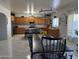 Open-concept kitchen and dining area with wood cabinets, stainless steel appliances, island seating, and modern lighting at 22966 W Hopi St, Buckeye, AZ 85326