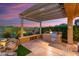 Backyard patio with a complete outdoor kitchen, charming rock waterfall feature, and covered patio for entertaining guests at 28375 N 130Th Dr, Peoria, AZ 85383