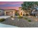 Beautiful desert home featuring stone accents, a well-manicured yard, and vibrant sunset backdrop at 28375 N 130Th Dr, Peoria, AZ 85383