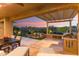 Inviting outdoor patio with built-in grill, waterfall feature, and serene desert views at sunset at 28375 N 130Th Dr, Peoria, AZ 85383