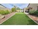 Spacious backyard featuring artificial grass, patio area, and mature landscaping at 3002 W Caravaggio Ln, Phoenix, AZ 85086