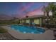 Twilight view of the backyard pool, illuminated and surrounded by decorative rock and fencing at 5330 E Tierra Buena Ln, Scottsdale, AZ 85254