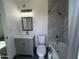 Modern bathroom features a gray vanity, toilet, and shower-tub with marble style tile at 5539 W Wilshire Dr, Phoenix, AZ 85035