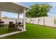 Backyard oasis featuring low-maintenance artificial turf, a covered patio, and privacy walls at 7064 W Lincoln St, Peoria, AZ 85345