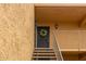 Second floor tan condo building with a floral wreath hanging on the front door near exterior sconce lights at 8500 E Indian School Rd # 233, Scottsdale, AZ 85251