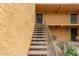 Staircase leading to tan second floor units in a condo building with sconce lights and bench at 8500 E Indian School Rd # 233, Scottsdale, AZ 85251