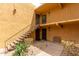 Tan building with stairs leading up to second floor condos and small patio with a bench for residents at 8500 E Indian School Rd # 233, Scottsdale, AZ 85251