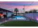 Inviting backyard with a sparkling pool, turf, privacy fence, and ambient string lights for evening relaxation at 8728 E Monte Vista Rd, Scottsdale, AZ 85257