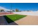 A simple backyard with a grass area and a high concrete wall at 8802 W Monterey Way, Phoenix, AZ 85037