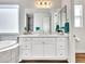 Bathroom featuring dual sinks, vanity, and a bathtub with shower and natural light at 9157 W Country Club Trl, Peoria, AZ 85383