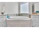Corner bathtub with marble tile and window with coverings and dual sink vanity in the background at 9157 W Country Club Trl, Peoria, AZ 85383
