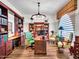 A warm office featuring built-in bookshelves, a large desk, a statement light fixture and wood floors at 9157 W Country Club Trl, Peoria, AZ 85383