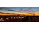 Panoramic sunset view over desert landscape with fence and outdoor lights at 10109 E Trailhead Ct, Gold Canyon, AZ 85118