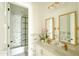 Bright, stylish bathroom with marble tiling, double sinks, gold fixtures, and a glass-enclosed shower at 10344 E Trillium Ave, Mesa, AZ 85212