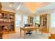 Bright office with a chandelier, built-in bookshelves, large windows, and a classic wooden desk at 10344 E Trillium Ave, Mesa, AZ 85212