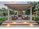 Outdoor fireplace featuring an outdoor seating area, pergola, manicured lawn, and lush landscaping at 10344 E Trillium Ave, Mesa, AZ 85212