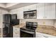 Updated kitchen with granite countertops, stainless steel microwave and cooktop, and white cabinets for storage at 1332 E Redfield Rd, Tempe, AZ 85283
