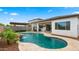 Stunning backyard with a pool, rock waterfall, covered patio, and lush artificial turf, ideal for entertaining at 14587 W Alexandria Way, Surprise, AZ 85379