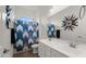 Bathroom featuring a double sink vanity and decorative blue shower curtain adding style to the space at 14587 W Alexandria Way, Surprise, AZ 85379