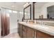 Bright bathroom featuring a dual sink vanity with granite countertops and warm wood cabinetry at 17970 N 114Th Ln, Surprise, AZ 85378