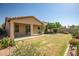 Expansive backyard featuring a covered patio, lush lawn, and meticulously manicured landscaping at 17985 W Ivy Ln, Surprise, AZ 85388