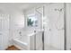 Bathroom featuring a combined shower and tub with sleek glass door and bright window at 17985 W Ivy Ln, Surprise, AZ 85388