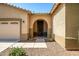 Inviting front entrance with an arched doorway and a well-maintained landscape, plus a two car garage at 17985 W Ivy Ln, Surprise, AZ 85388