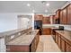Modern kitchen featuring granite countertops, stainless steel appliances, and brown cabinets, open to the living area at 17985 W Ivy Ln, Surprise, AZ 85388