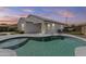 View of the beautiful backyard pool, covered patio, and desert landscaping at dusk at 19203 W Jackson St, Buckeye, AZ 85326