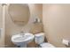Cozy powder room features a pedestal sink, round mirror, and neutral color palette at 2042 W Mark Ln, Phoenix, AZ 85085