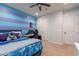 Bedroom with blue striped accent wall, ceiling fan, carpet, and gaming area with desk and ergonomic chair at 22771 N 98Th Dr, Peoria, AZ 85383