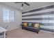 Bright bedroom with a striped accent wall, a comfortable sofa, and a work desk at 22771 N 98Th Dr, Peoria, AZ 85383