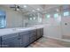 The main bathroom offers double sinks, gray cabinets, a large mirror, and a luxurious walk-in shower at 22771 N 98Th Dr, Peoria, AZ 85383