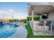 An outdoor kitchen features bar seating, TV, and built in grill that overlooks a lush pool and spa area at 22771 N 98Th Dr, Peoria, AZ 85383