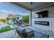 Outdoor living space with a covered patio, fireplace, TV, dining set and barbecue area at 22771 N 98Th Dr, Peoria, AZ 85383