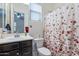 Beautiful bathroom with brown cabinets and a shower with a floral shower curtain at 22960 N 94Th Ln, Peoria, AZ 85383